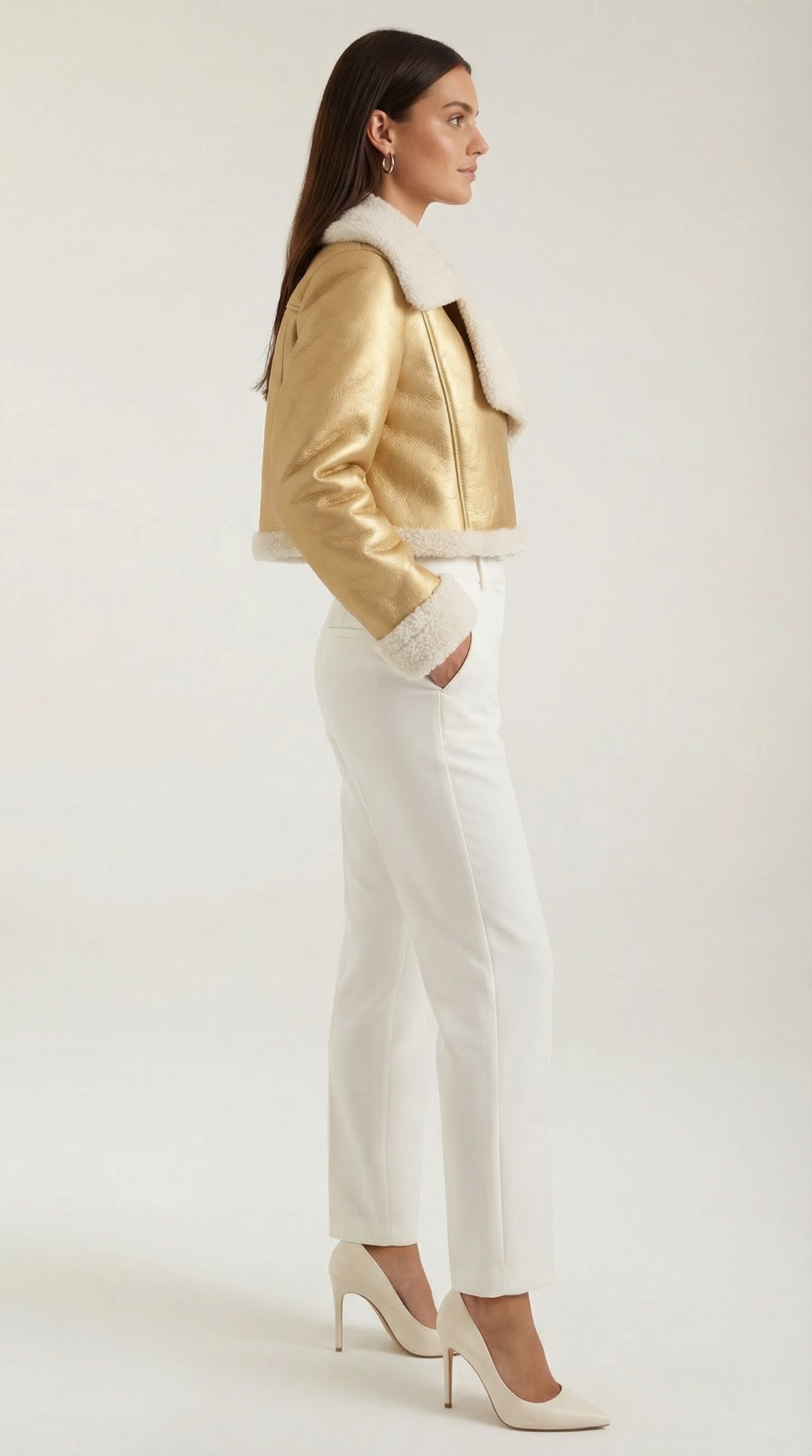 Gold cropped leather aviator jacket with plush white shearling trim, worn with white trousers and heels.
