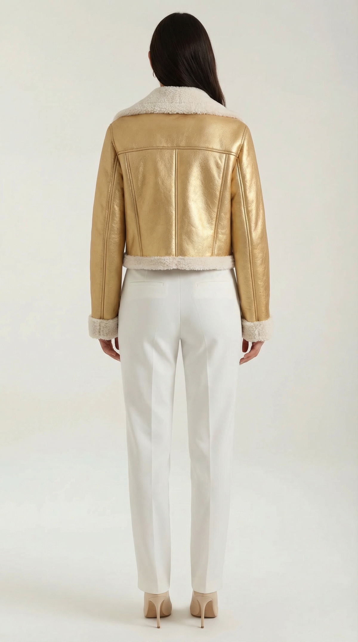 Gold leather aviator jacket with a cropped silhouette, plush shearling trim, and white trousers.