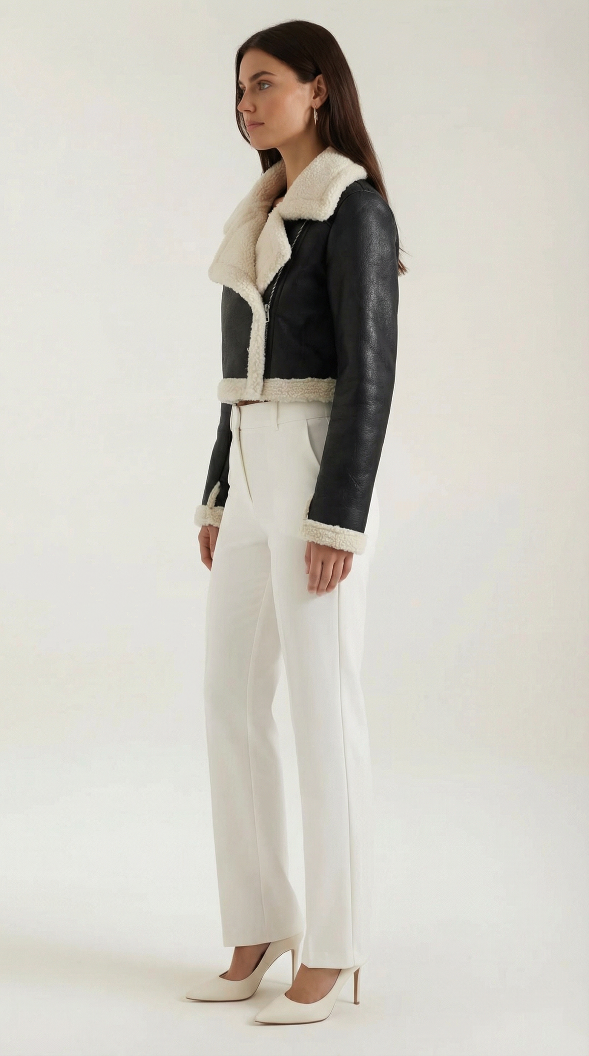 Black leather aviator jacket with a cropped fit, cream shearling trim, and zip-up front, styled with white trousers.