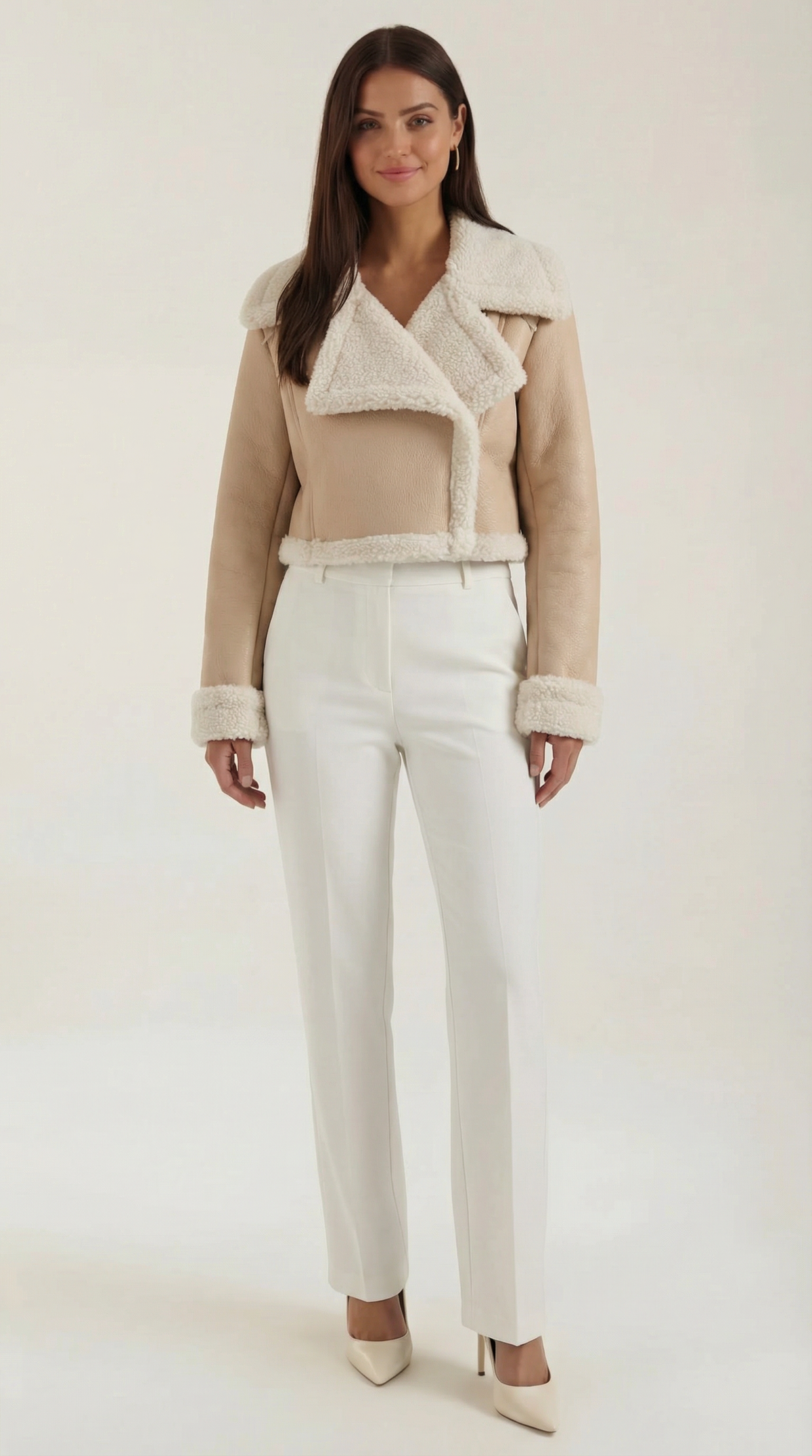 Beige cropped leather aviator jacket with plush white shearling trim on the collar, cuffs, and hem, worn with white trousers.