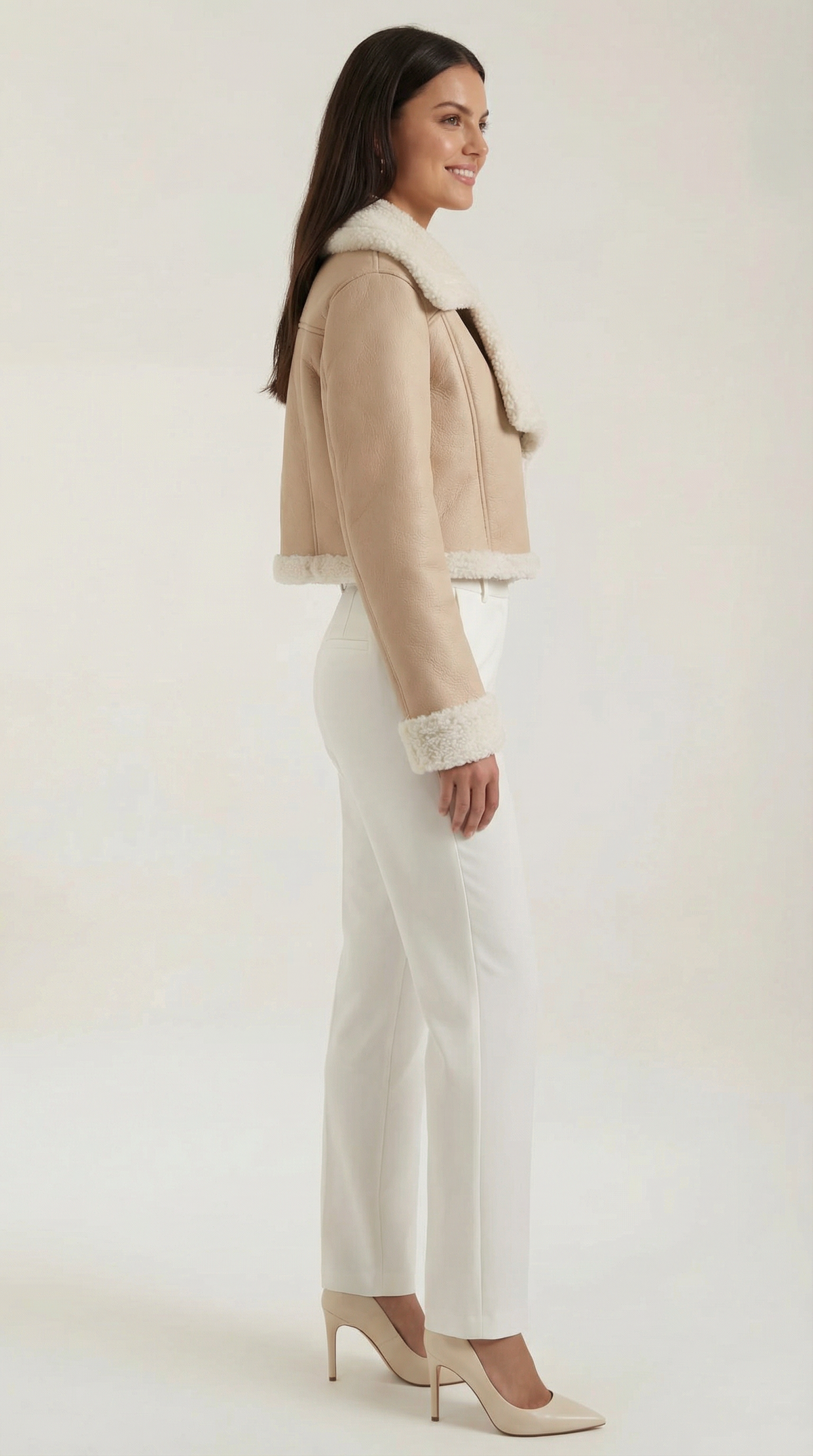 Beige cropped leather aviator jacket with plush shearling trim on the collar, cuffs, and hem, worn with white trousers.