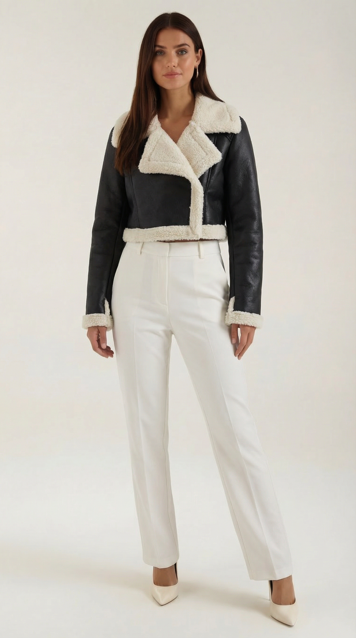 Black cropped leather aviator jacket with plush white shearling trim, worn with tailored white trousers.