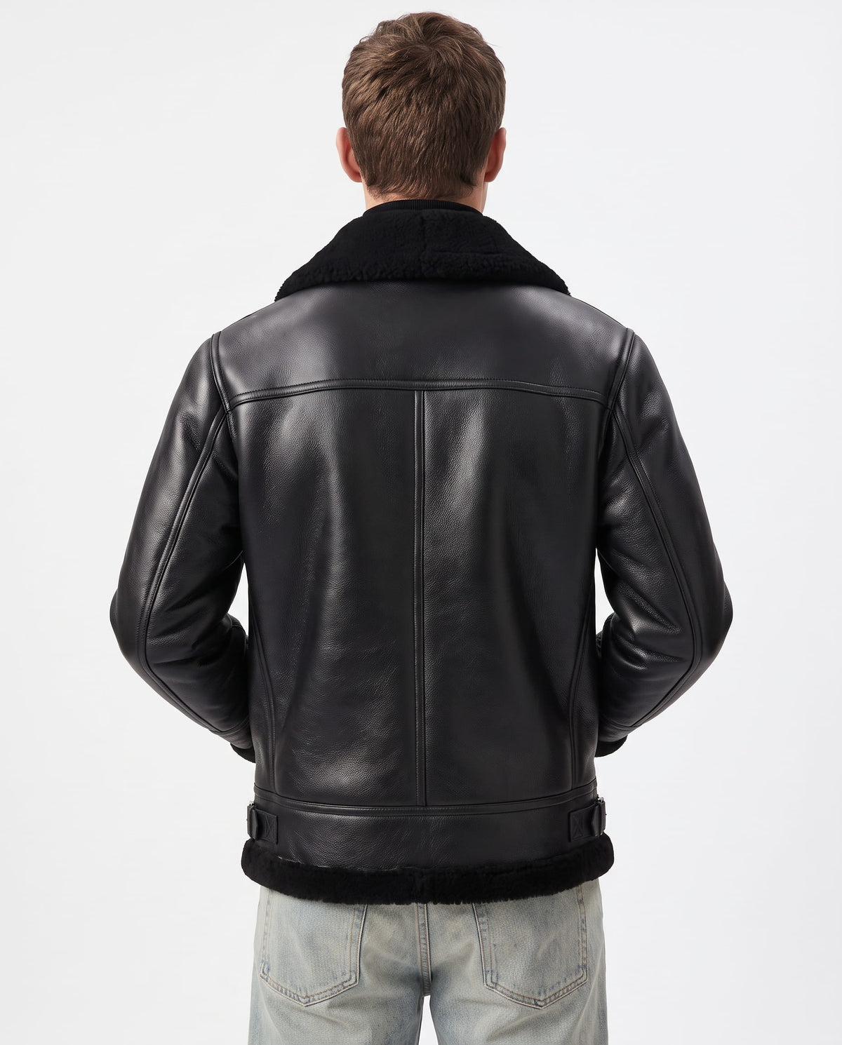 Back view of a black leather aviator jacket featuring a plush shearling collar and hem, worn over light-wash denim jeans.