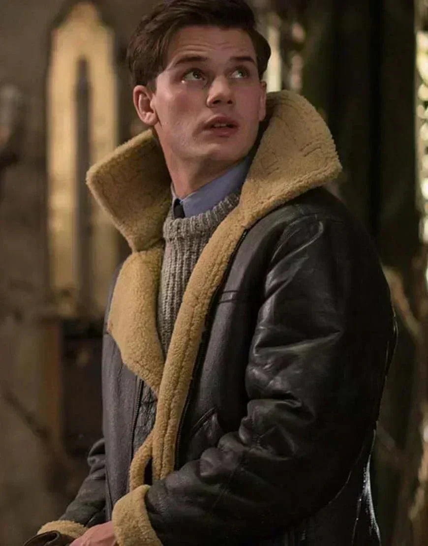 A man wearing a brown leather aviator jacket with shearling lining and a full-zip front, standing indoors