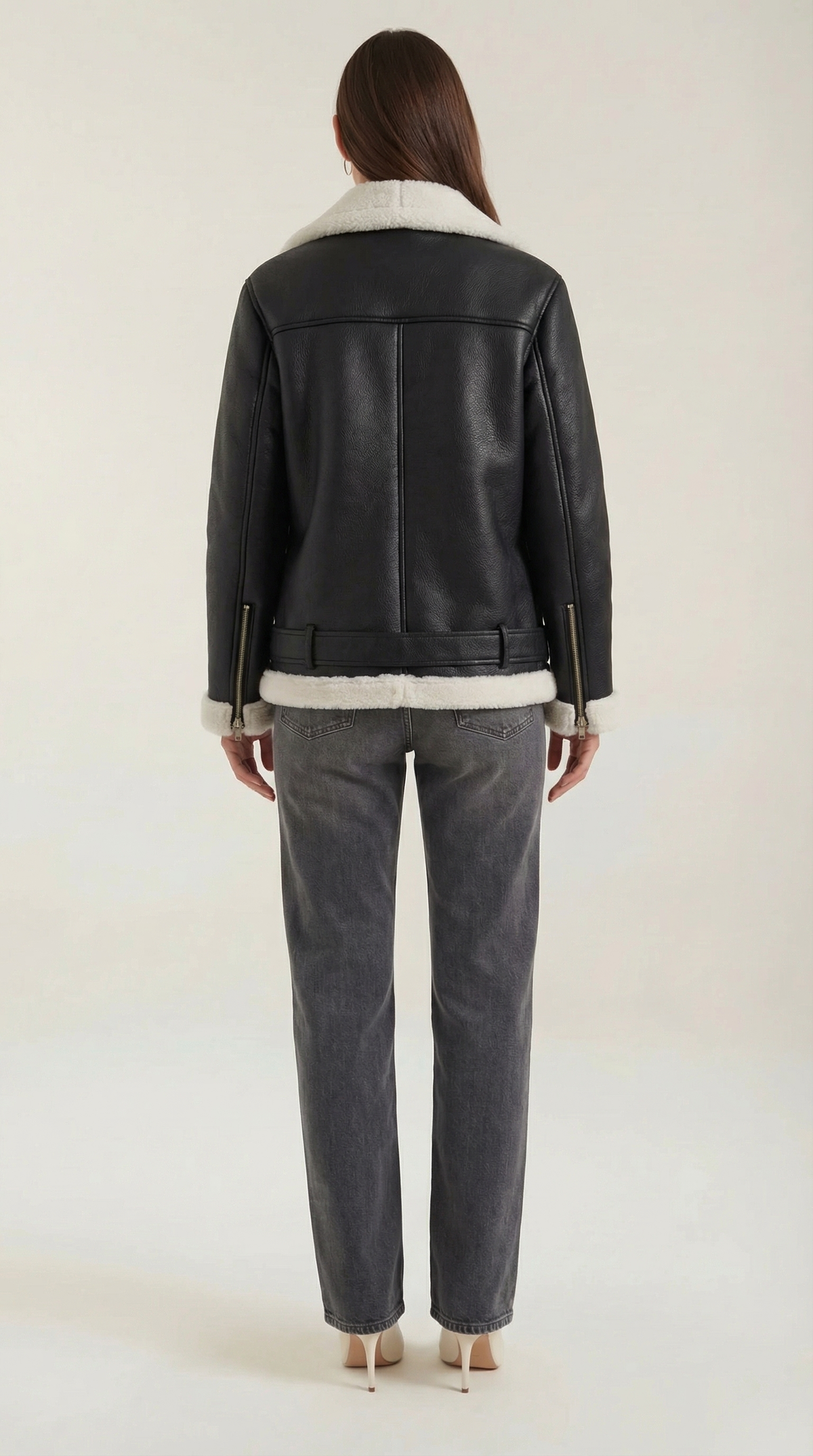 Black and white  leather aviator jacket with white shearling trim, belted hem, and zip cuffs worn with grey jeans.
