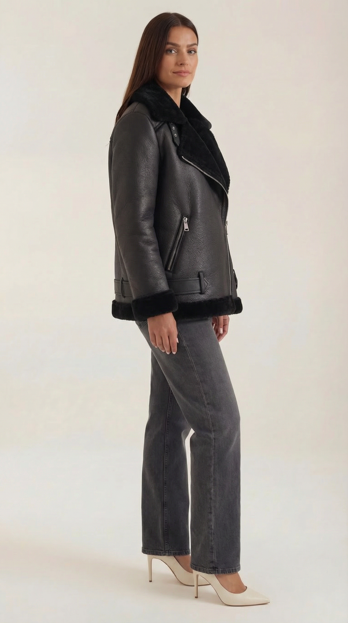 Black leather aviator jacket with shearling trim, diagonal zip front, and belted hem worn with grey jeans.
