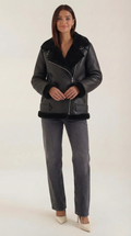 Black leather aviator jacket with plush shearling trim, diagonal zip front, and adjustable belted hem.