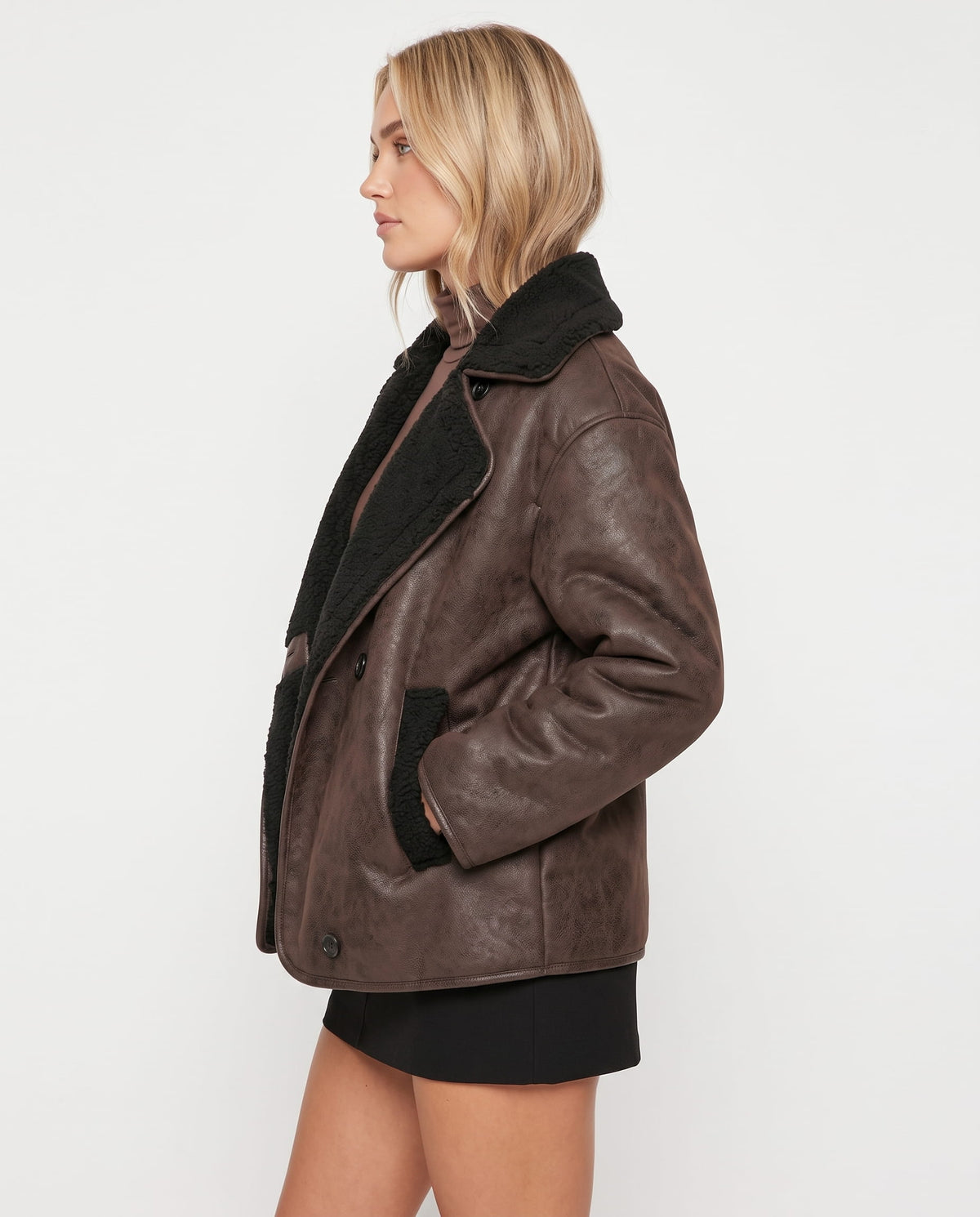 Brown leather aviator jacket with an oversized fit, wide lapels, and plush black sherpa lining and collar.