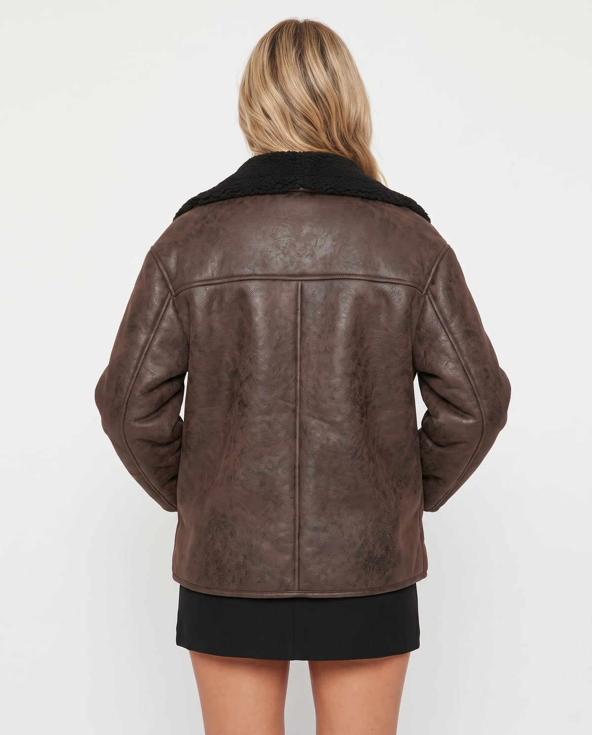 Back view of an oversized brown leather aviator jacket featuring a plush black sherpa collar and textured finish.