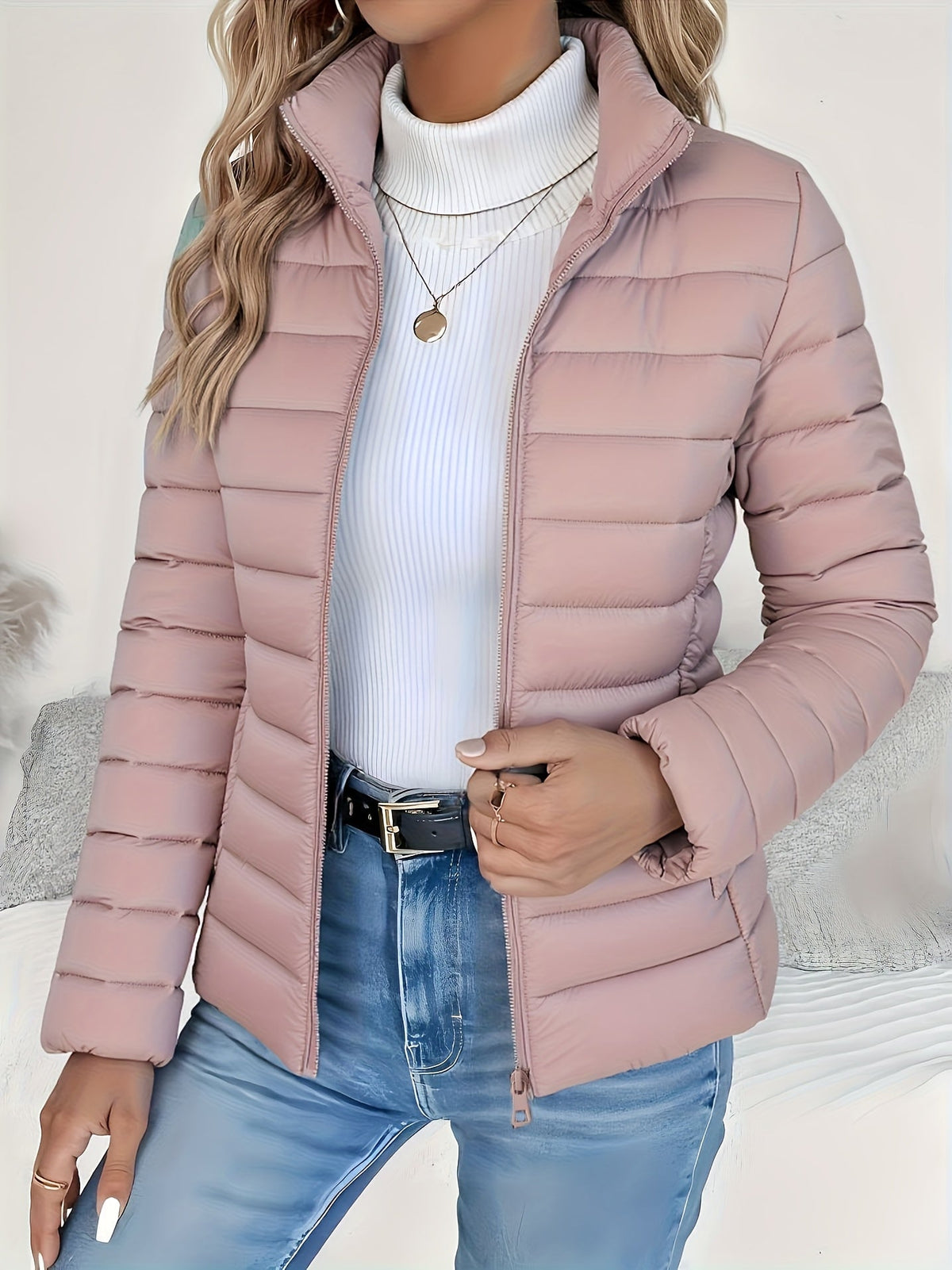 Blush pink slim-fit puffer jacket with horizontal channel quilting, stand collar, and zip front worn over a white turtleneck.