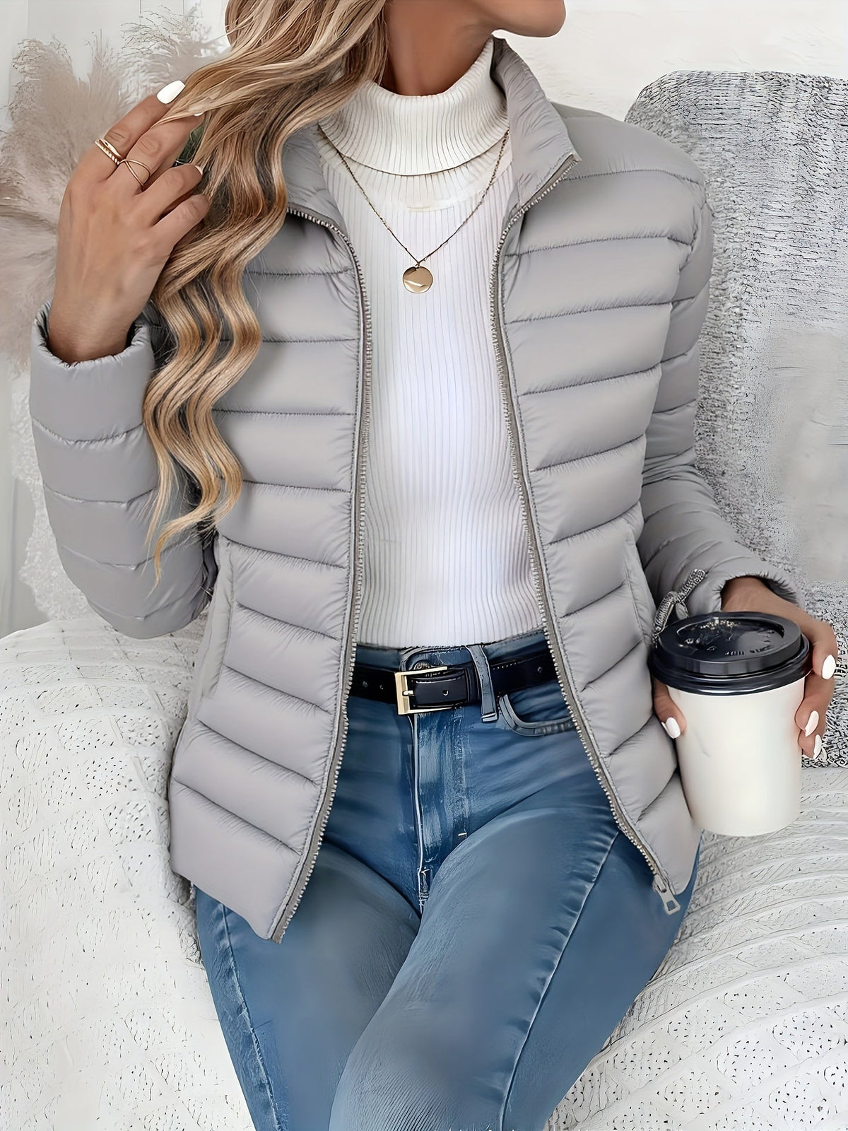 Light gray slim-fit puffer jacket with horizontal channel quilting, stand collar, and full zip front worn over a turtleneck.