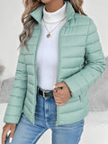 Sage green slim-fit puffer jacket with horizontal channel quilting, stand collar, and full zip front over a white turtleneck.