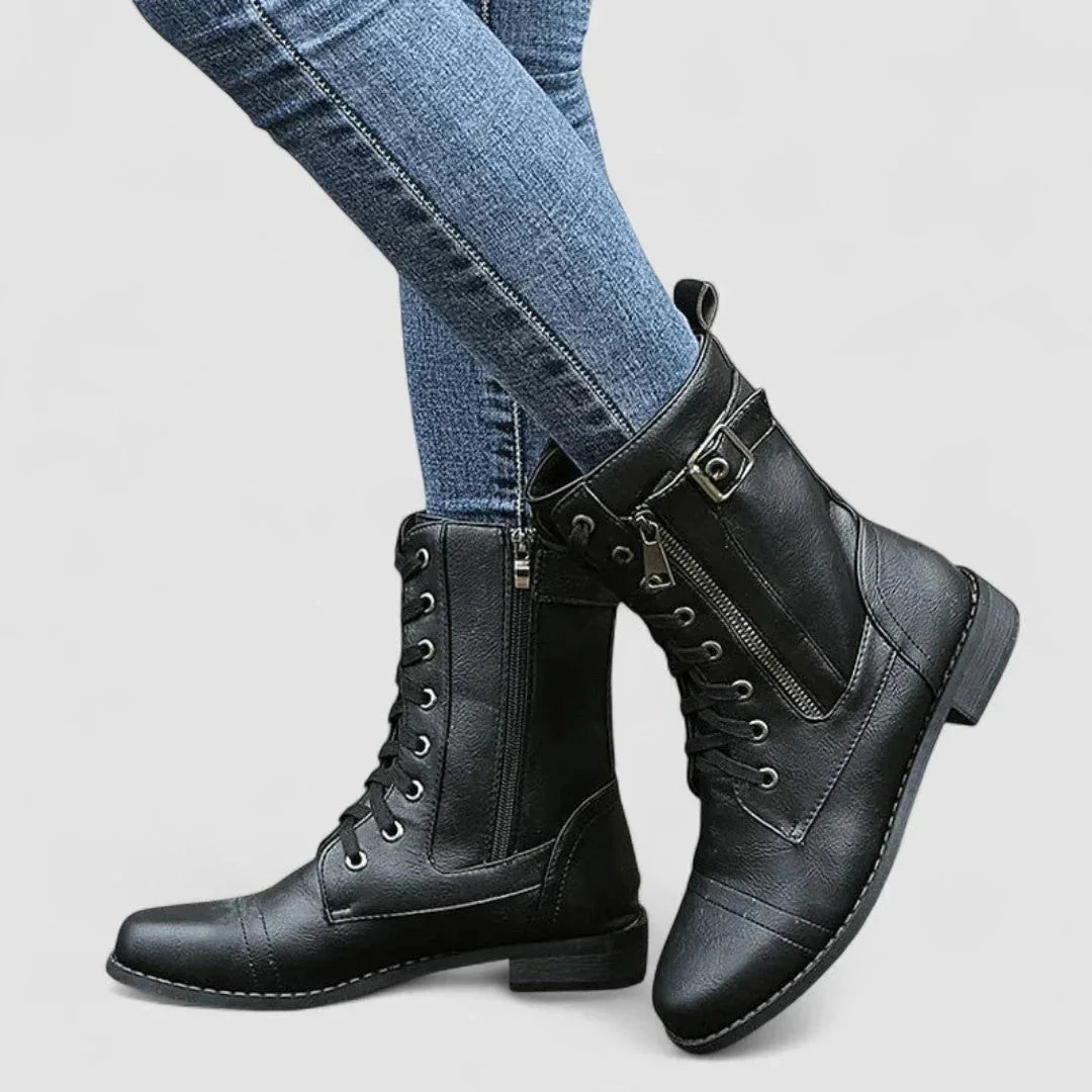 Black grained mid-calf combat boots with lace-up front, side zip, cap toe, and adjustable buckle strap.