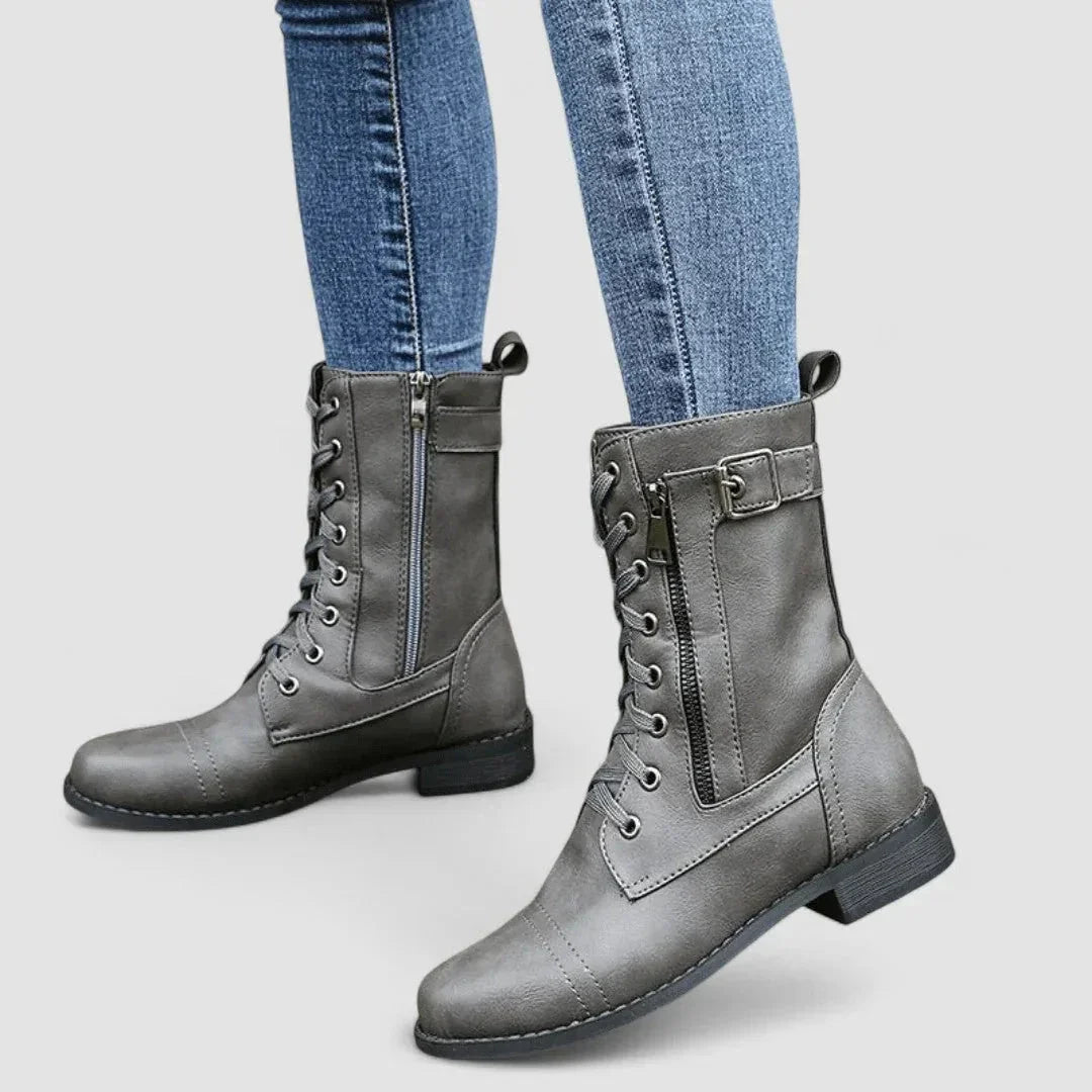 Grey grained mid-calf combat boots with lace-up front, side zip, cap toe, and adjustable buckle strap.