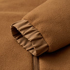 Tan polar fleece jacket sleeve featuring a smooth, elasticized cuff and dense, pill-resistant fabric texture.