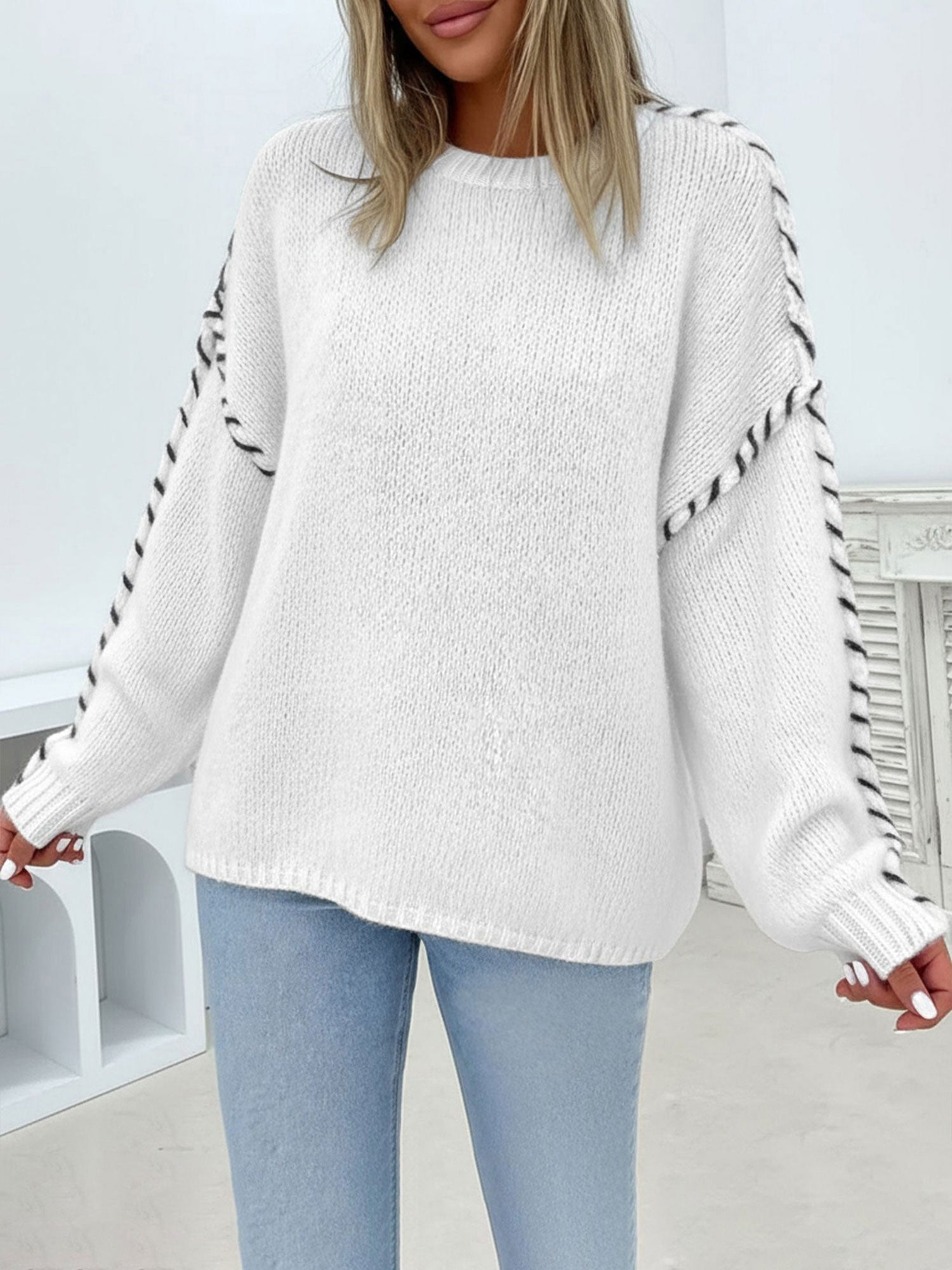 Oversized white crew-neck sweater in soft knit with contrasting black whipstitch detailing along the sleeves.