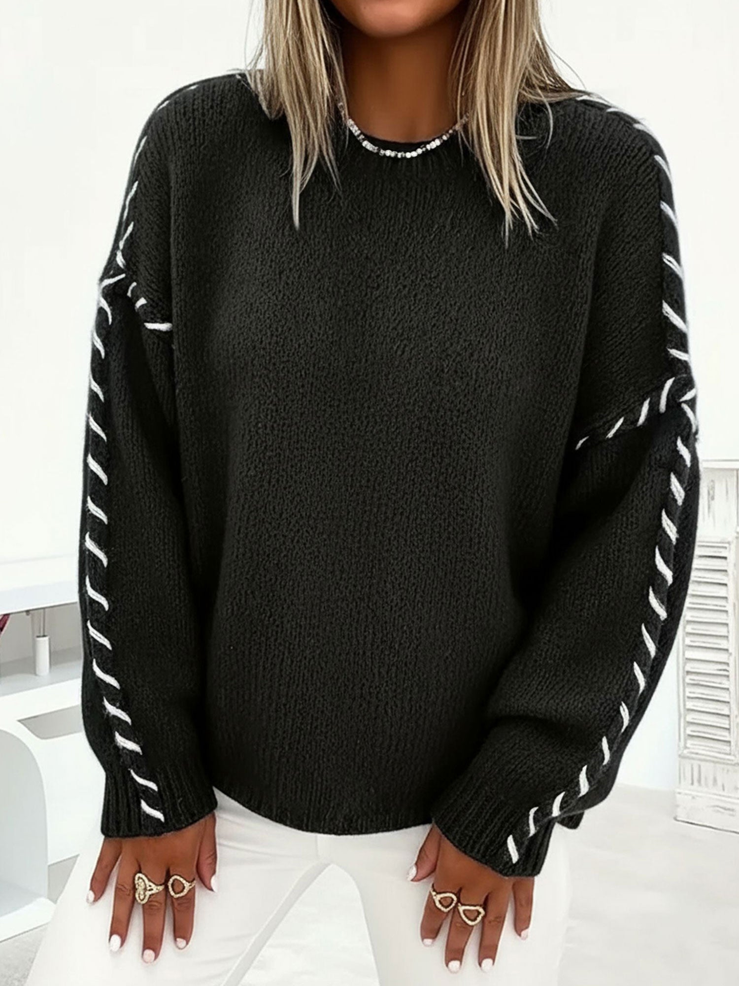 Black oversized crew-neck sweater in soft knit with contrasting white whipstitch detailing along the sleeves.