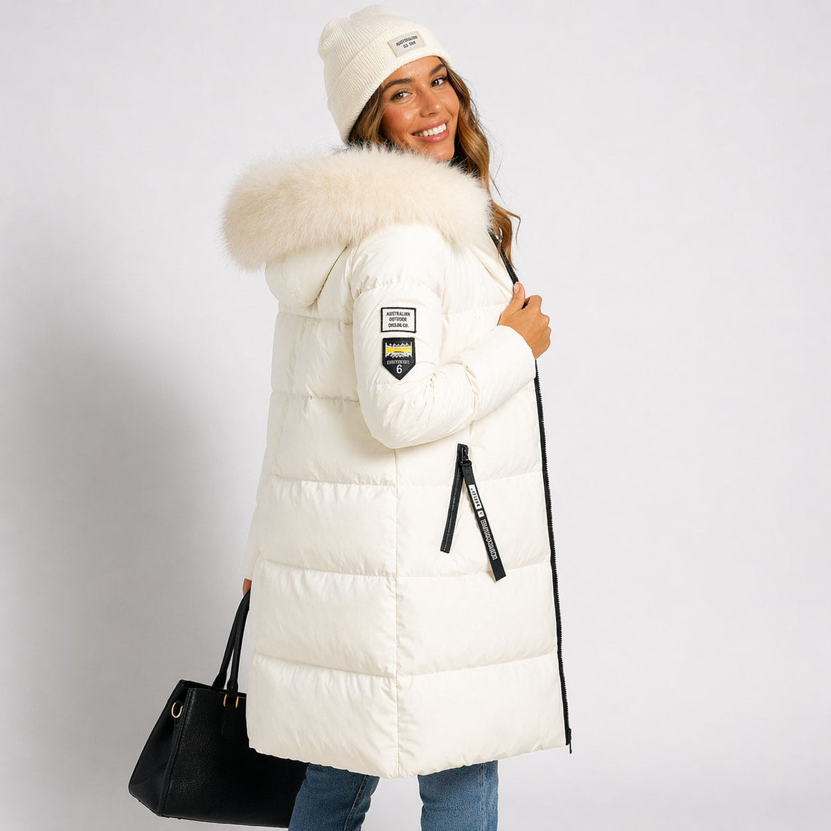 Cream longline quilted parka with a faux-fur trimmed hood, two-way zip, and zip hand pockets, worn with a matching beanie.