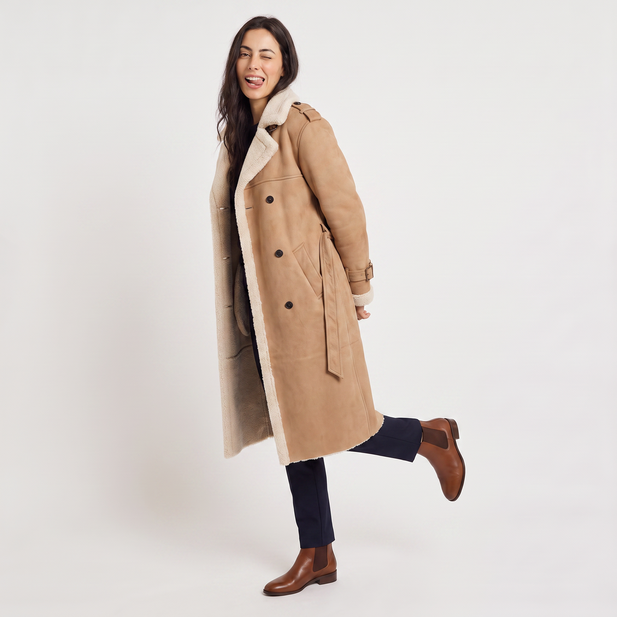 A woman wearing a tan longline leather aviator coat with borg trim and tie waist, shown in side view