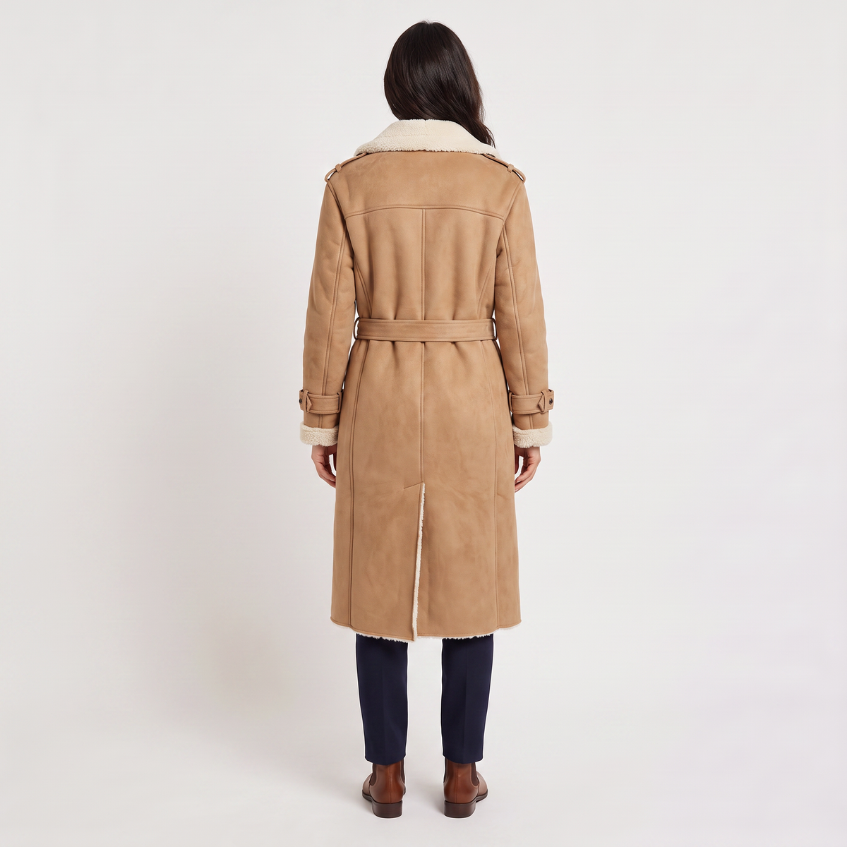 A woman wearing a tan longline leather aviator coat with a tie waist and borg trim, shown from the back