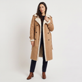 A woman wearing a tan longline leather aviator coat with borg trim, a tie waist, and double-breasted button front