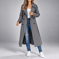 Gray longline trench coat with a double-breasted button front, wide notch lapels, and buttoned cuffs in an oversized fit.