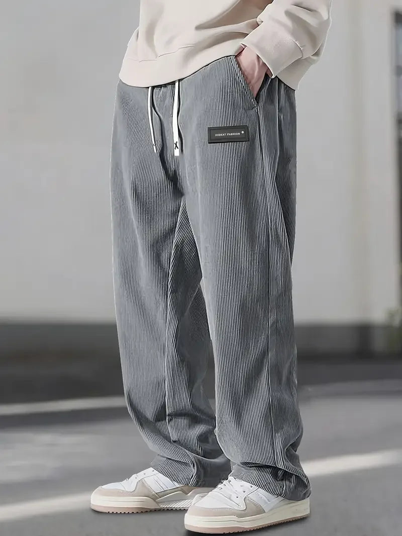 Gray ribbed corduroy pants with a loose, straight-leg fit, elastic drawstring waist, and slant side pockets.