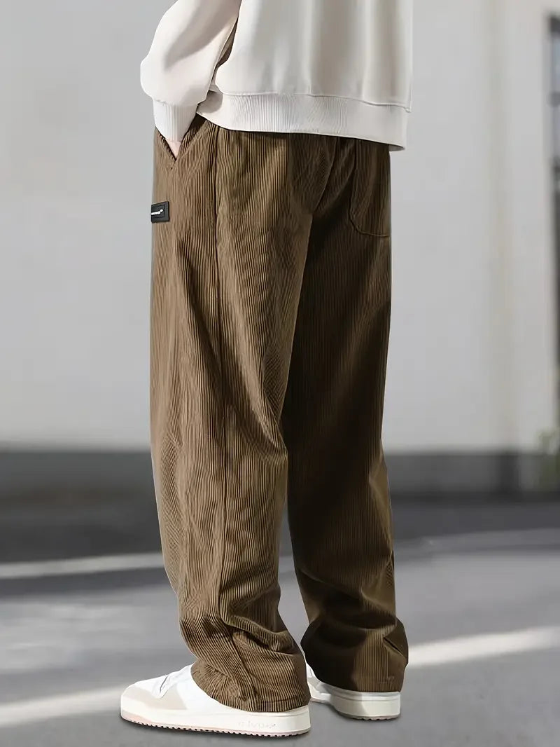 Brown loose-fit corduroy pants featuring a ribbed texture, elastic drawstring waist, and slant pockets.