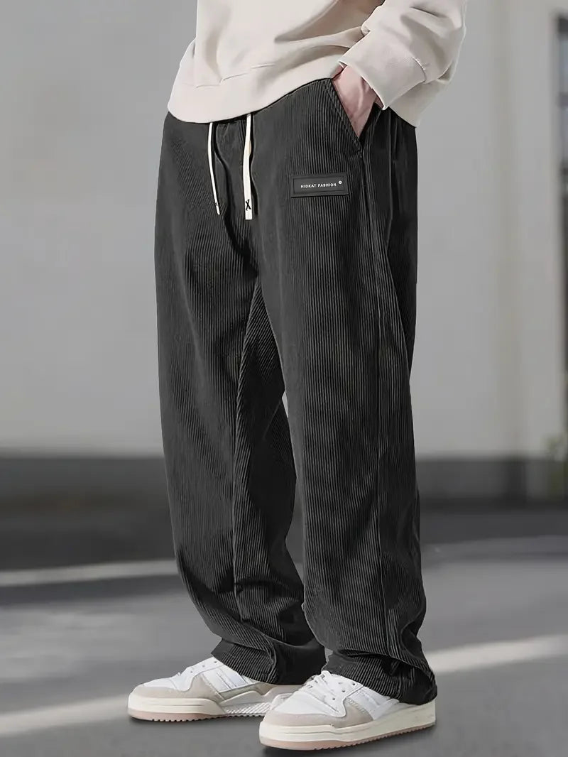 Loose-fit black corduroy pants with an elastic drawstring waist, slant pockets, and a straight-leg silhouette.