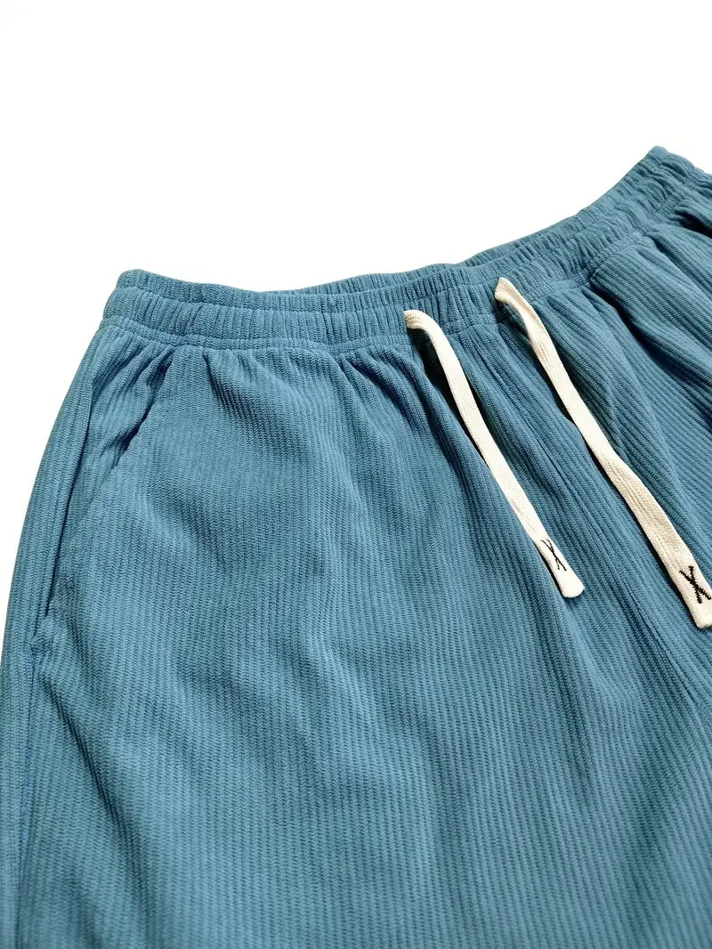 Blue corduroy pants featuring a ribbed texture, elastic drawstring waist, and slant side pockets.
