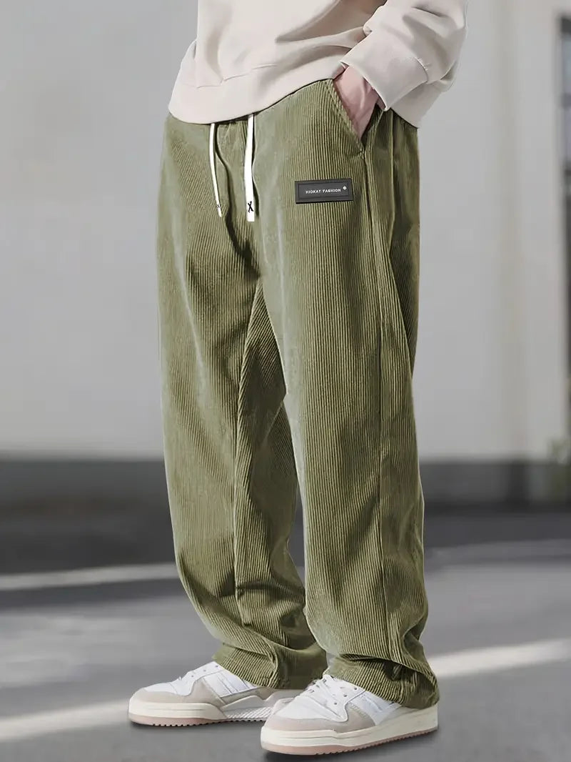 Olive green corduroy pants with a loose straight-leg fit, elastic drawstring waist, and slant side pockets.
