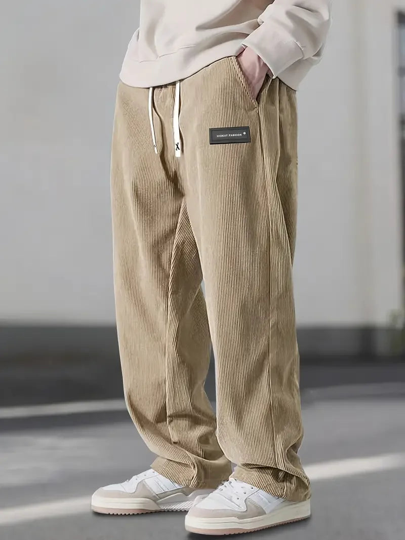Beige loose-fit corduroy pants with an elastic drawstring waist, slant pockets, and a relaxed straight-leg silhouette.