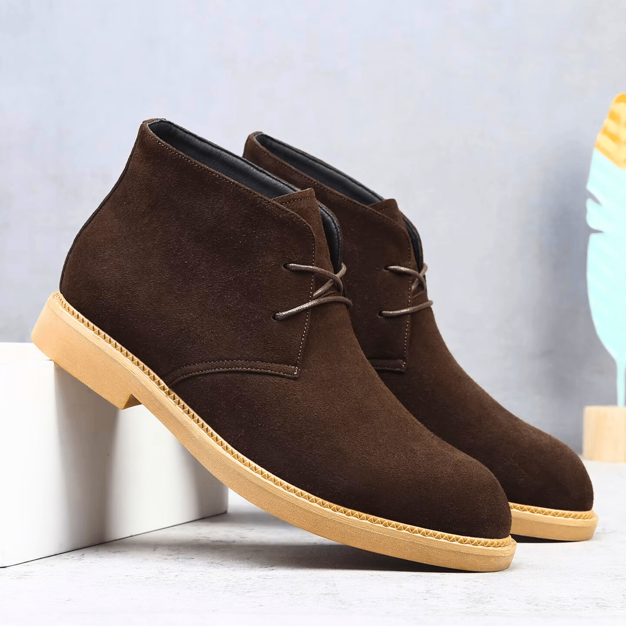 Dark brown suede-look desert boots with a plain toe, two-eyelet lacing, and a contrast tan welt-stitched sole.