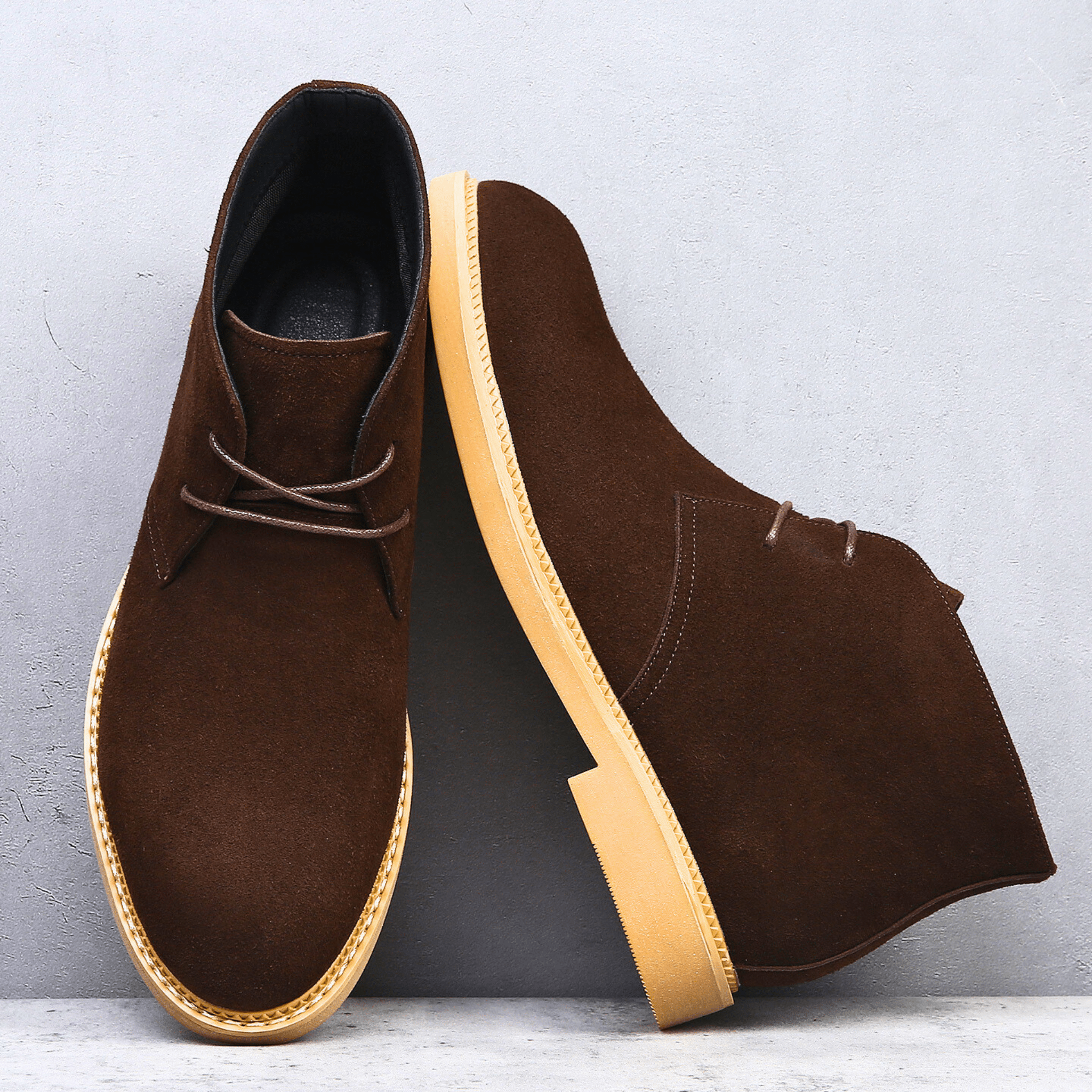 Dark brown suede-look desert boots with a plain toe, two-eyelet lacing, and a contrasting light-colored stacked sole.