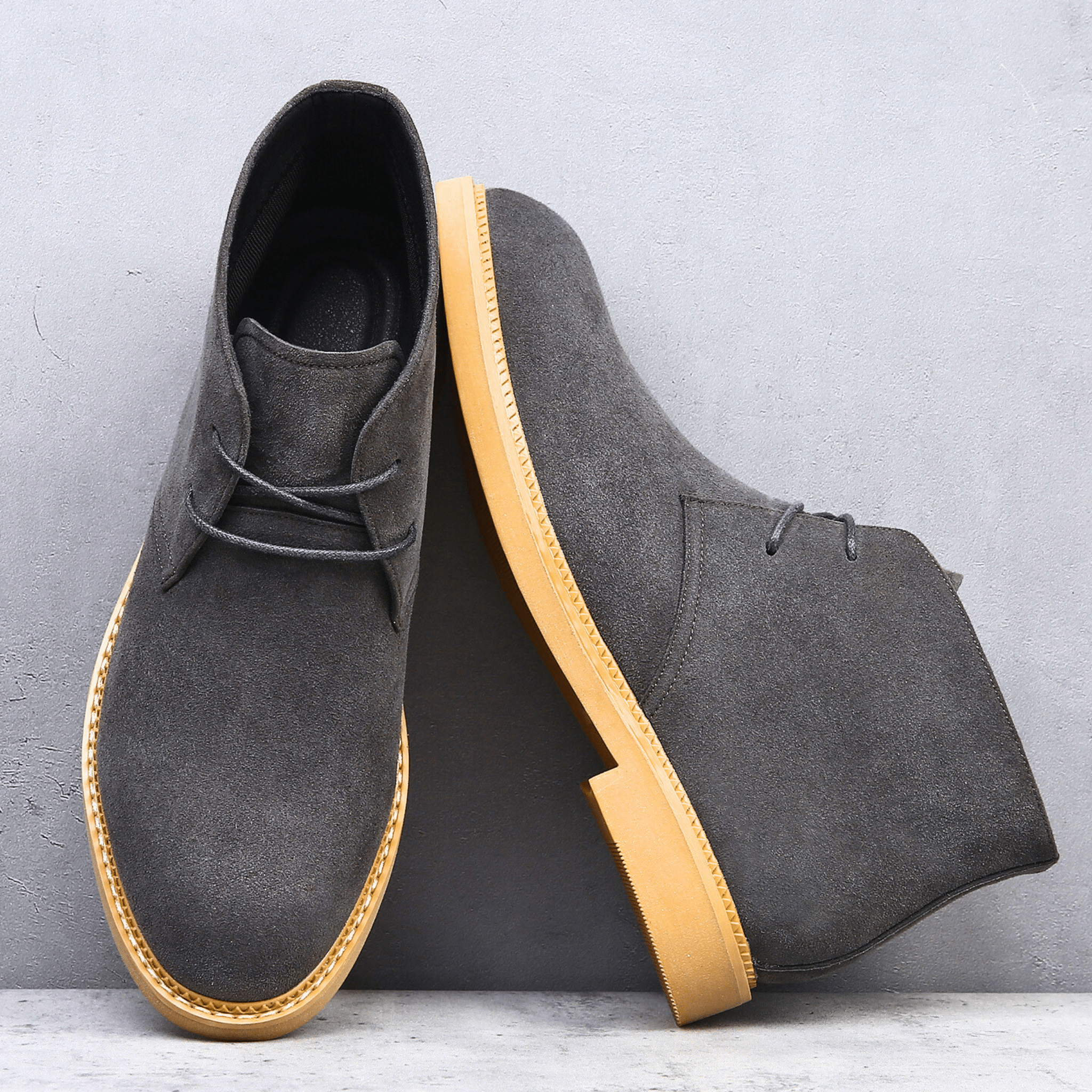 Charcoal grey suede-look desert boots with a plain toe, two-eyelet lacing, and a contrasting tan welt-stitched sole.