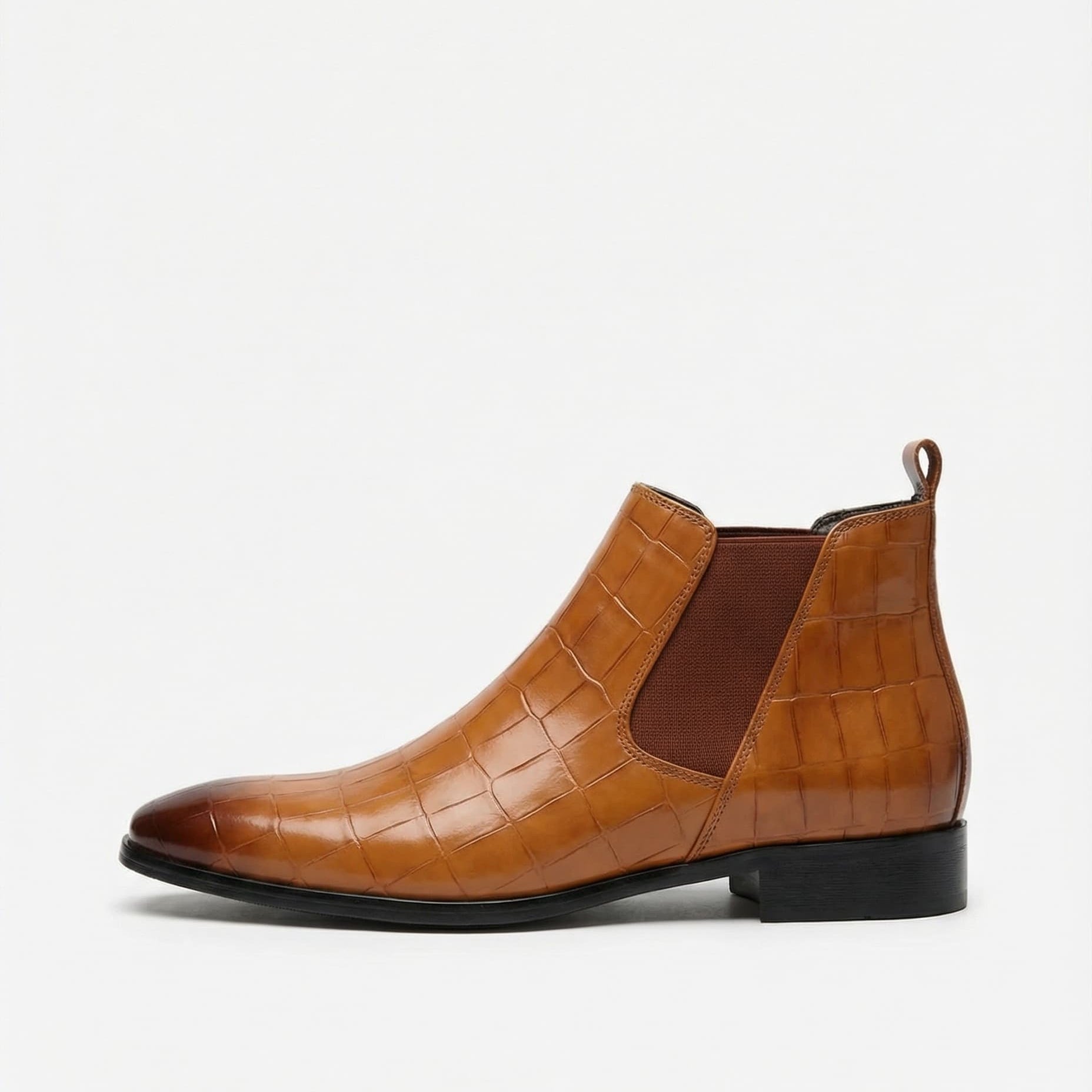 Tan croc-embossed Chelsea boots with a pointed toe, slim black outsole, and elastic side gore on a white background.
