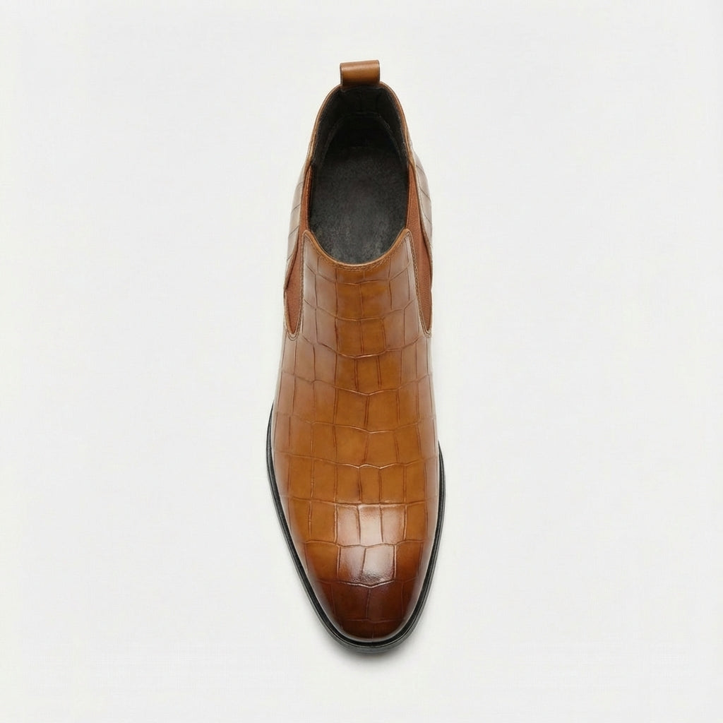 Tan croc-embossed leather Chelsea boots with a pointed toe, slim outsole, and rear pull tab on a white background.