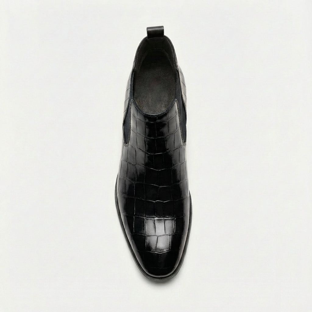 Black croc-embossed Chelsea boots featuring a sleek pointed toe, slim outsole, and elastic side gore detail.