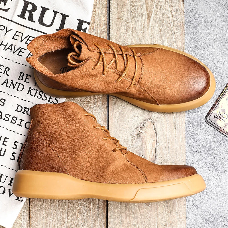 Tan leather chukka boots with a rounded toe, lace-up closure, and a thick, chunky rubber sole on a wooden surface.