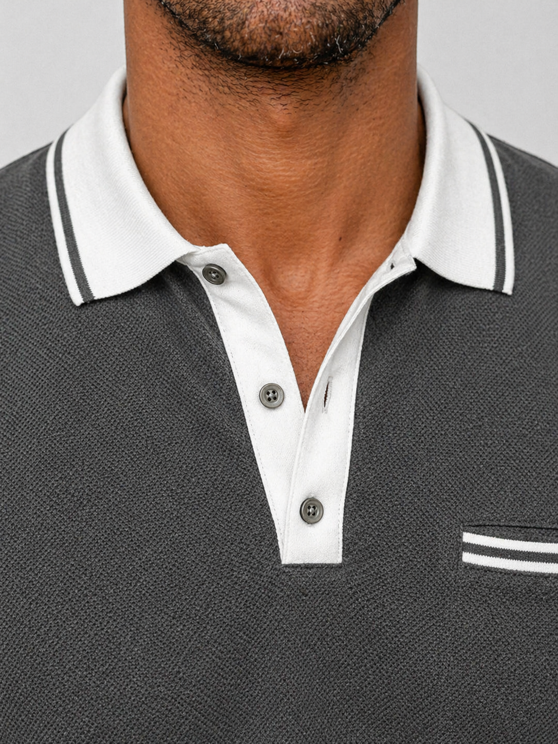 Charcoal knit long-sleeve polo with a white contrast collar, button placket, and subtle chest pocket detail.