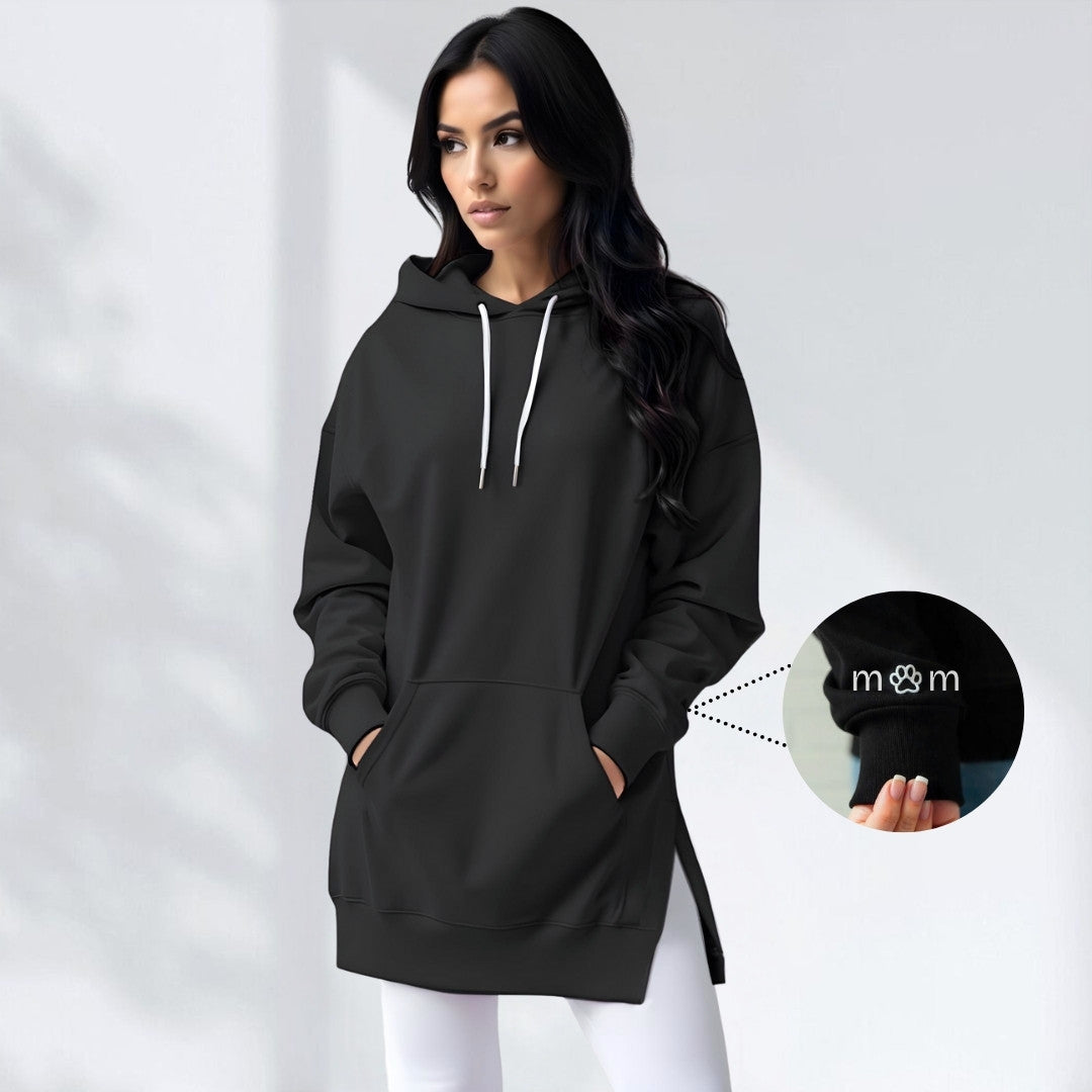 Oversized black brushed cotton hoodie with longline hem, side slits, drawstring hood, and embroidered cuff detail.