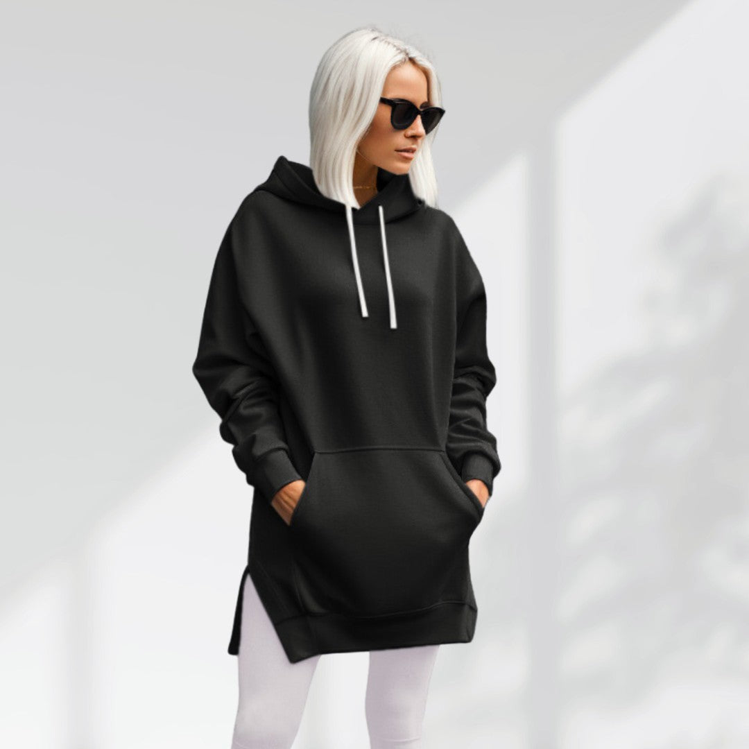 Oversized black brushed cotton hoodie with a longline hem, side slits, and a drawstring hood worn over white leggings.