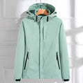 Mint green hooded waterproof jacket with a full-zip closure, adjustable hood, zippered pockets, and long sleeves displayed on a white background.