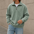 Sage green quarter-zip fleece sweatshirt with a stand collar and relaxed fit, paired with light blue jeans in a casual outdoor setting.