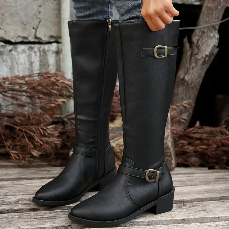 Black knee-high boots with structured shafts, antique brass buckles at the ankle and cuff, and a stacked block heel.