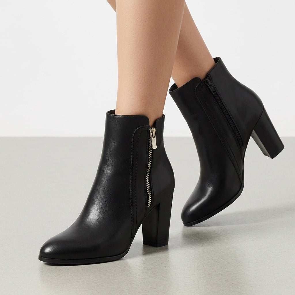Black grained ankle booties with a pointed toe, tall block heel, and side zip detail on a clean, neutral background.