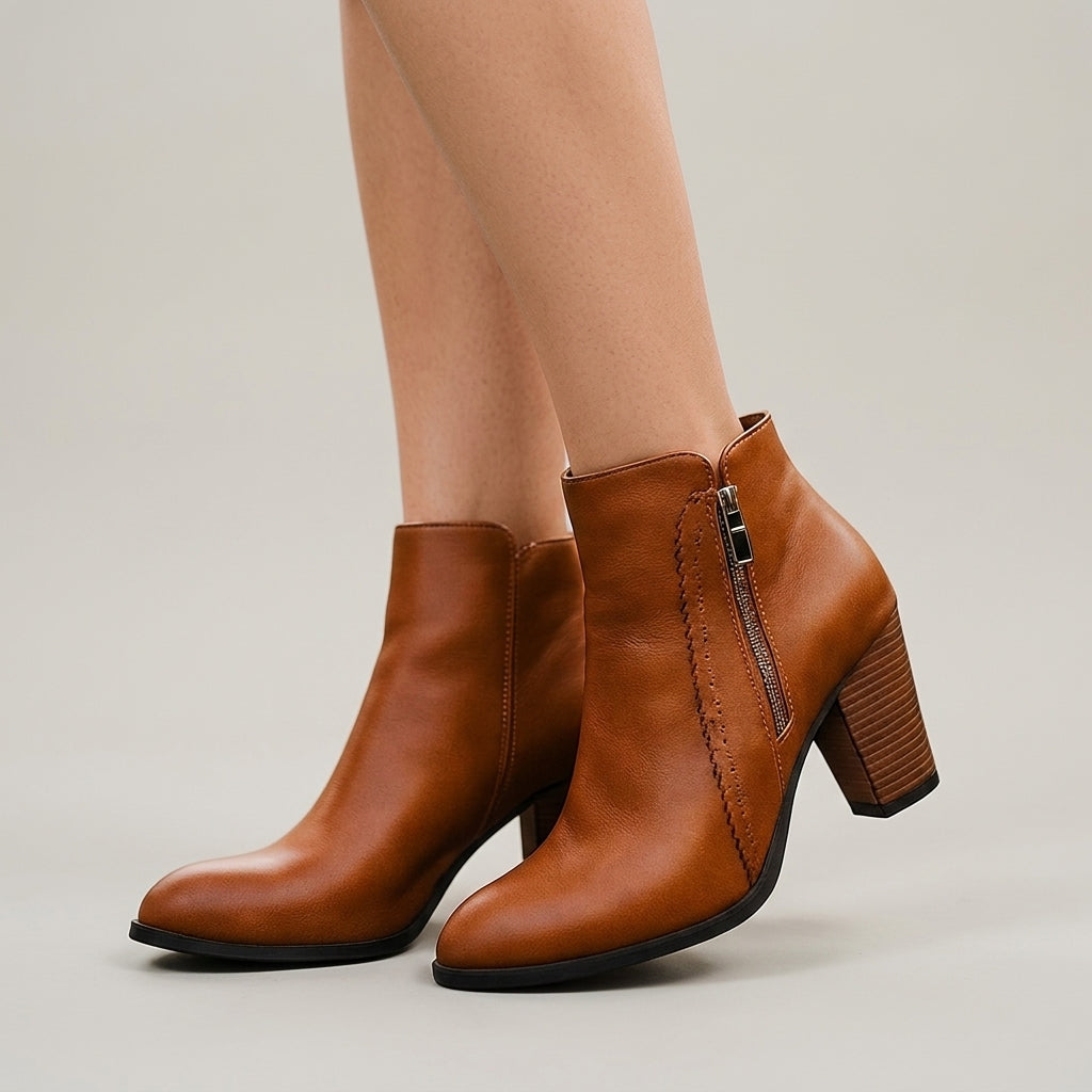 Tan grained ankle booties with a pointed toe, scalloped side topstitch, and a tall, squared block heel.