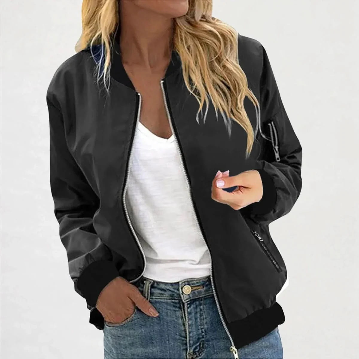Woman wearing a black bomber jacket featuring a zip-front closure, ribbed cuffs, and ribbed hem over a white tank top.