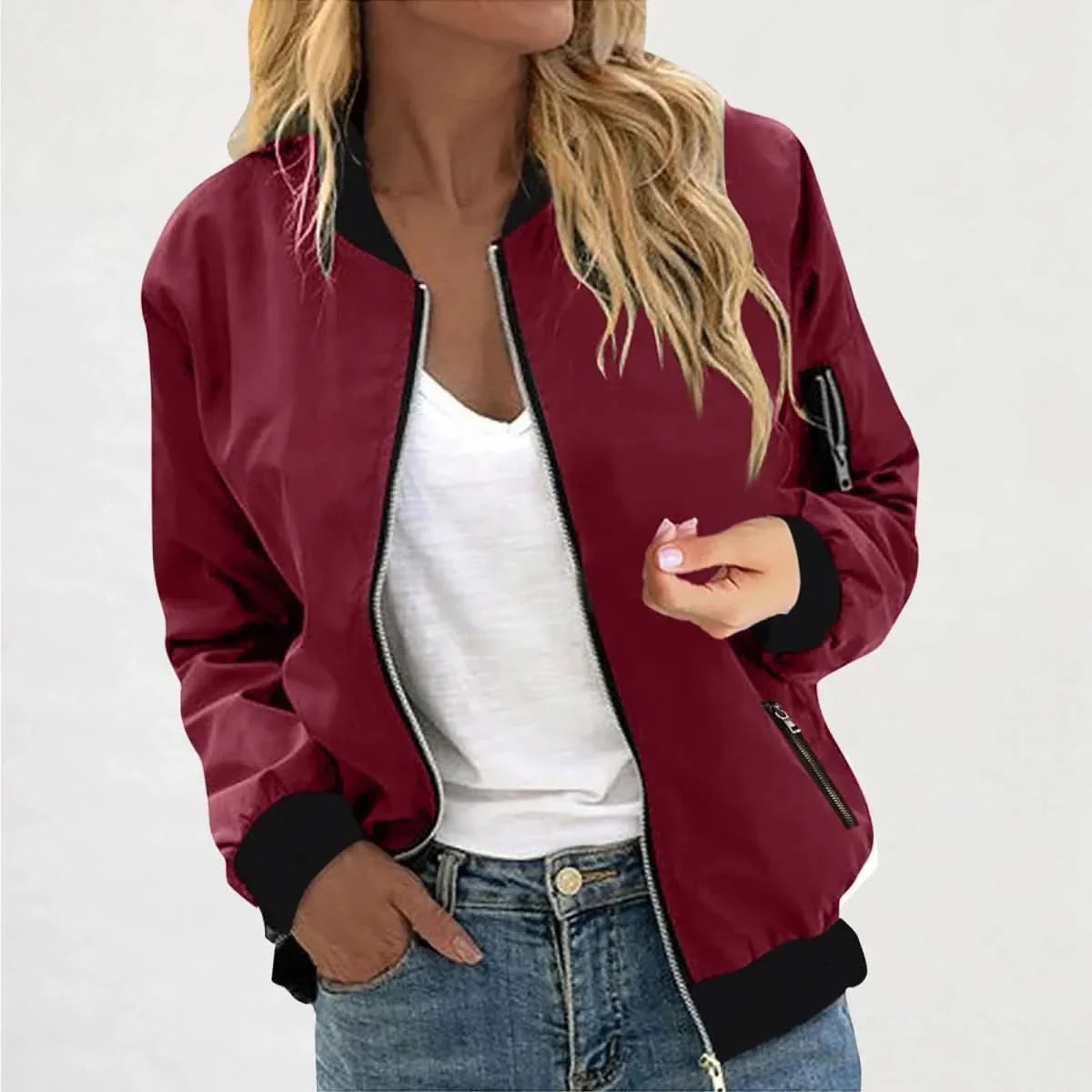 Woman wearing a red bomber jacket with a full-zip front, ribbed cuffs, and ribbed hem over a white tank top.