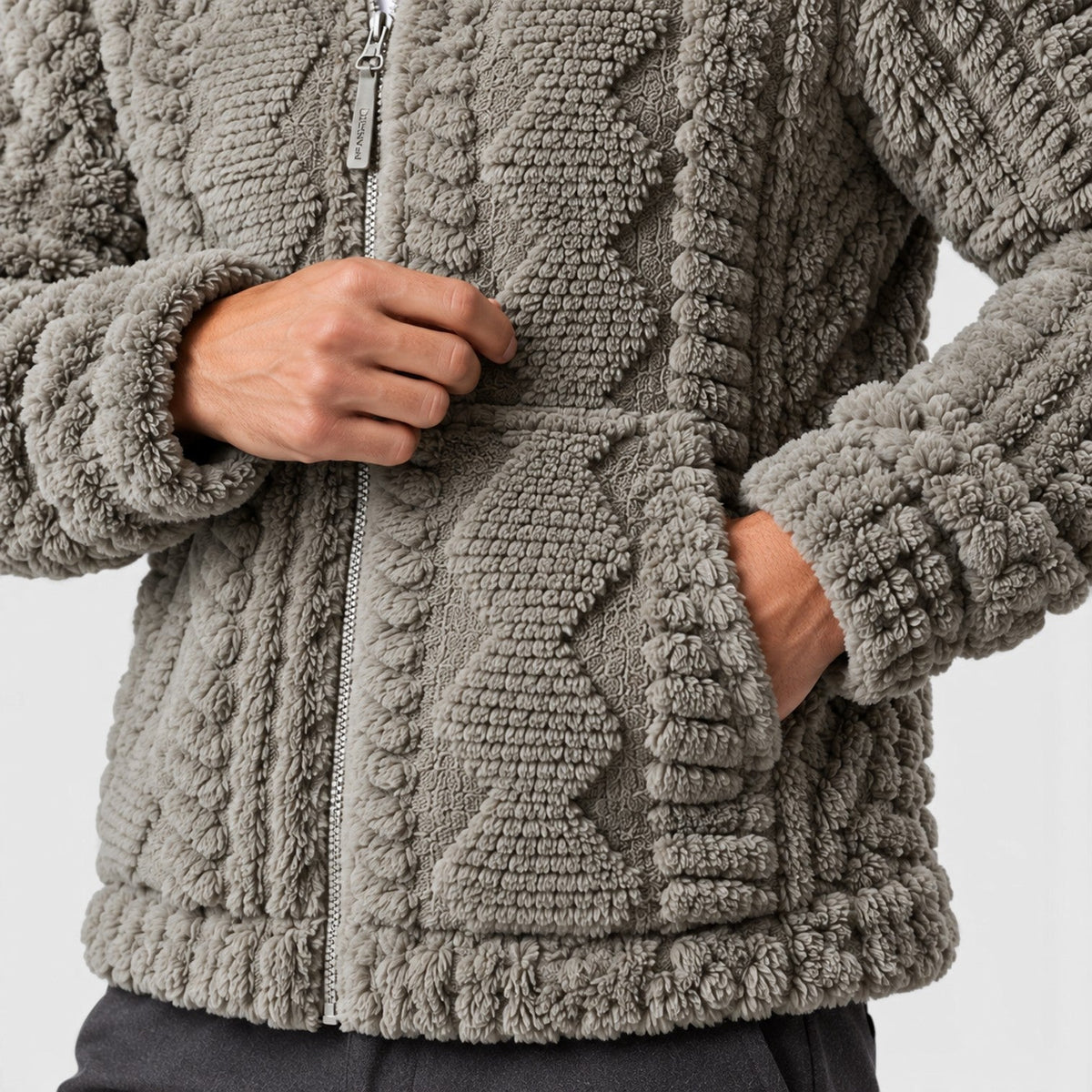 Close-up detail shot of the side hand pocket, front zipper, and cable pattern on a light gray fleece jacket.